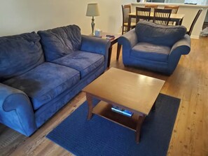 Un salon avec deux canapés bleus, une table basse en bois et un tapis bleu.