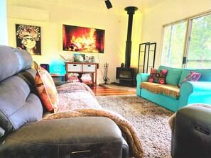 Una sala de estar con un sofá, una chimenea, una mesa con objetos y una ventana.