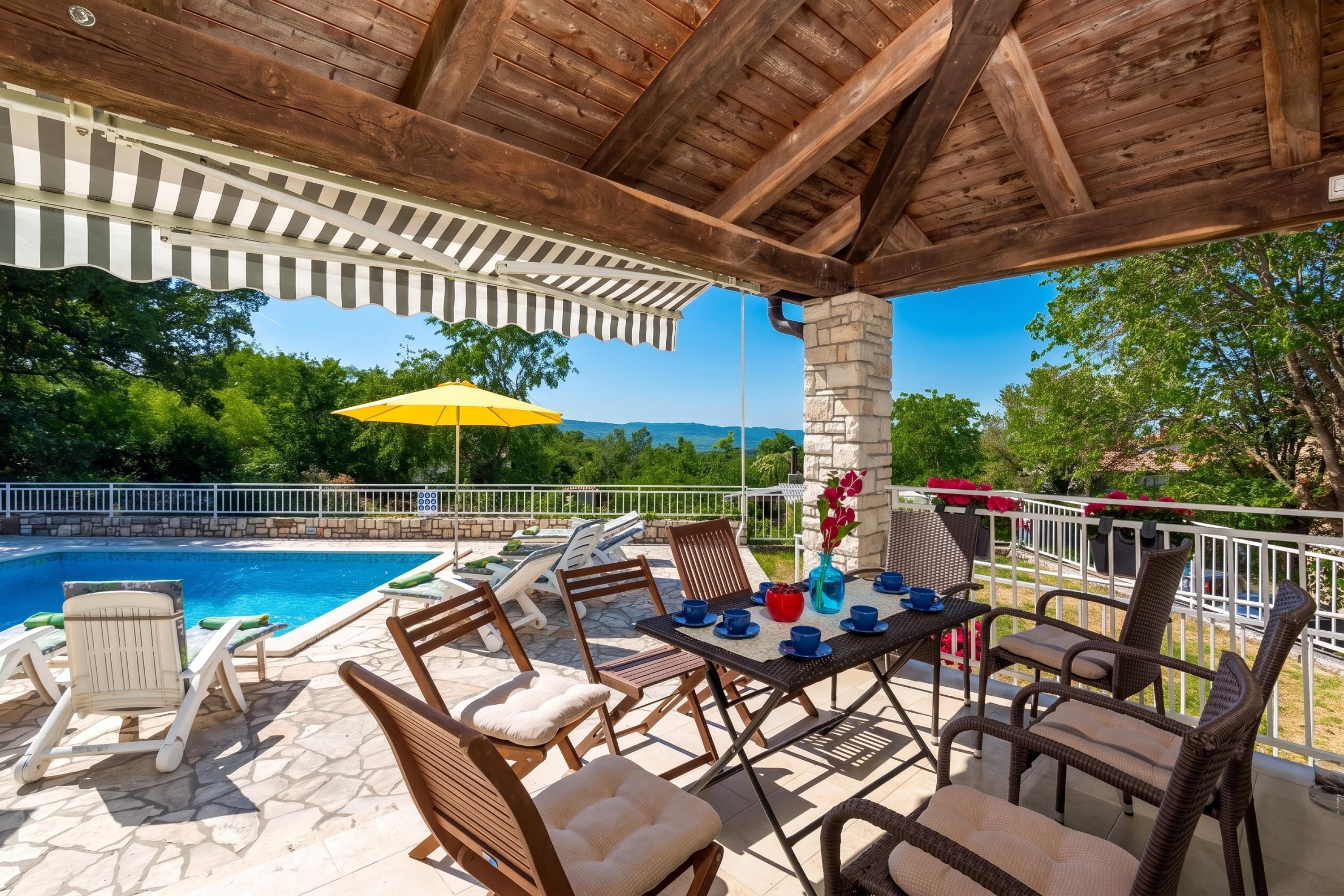 An outdoor patio area with a pool, lounge chairs, and a table set for dining.