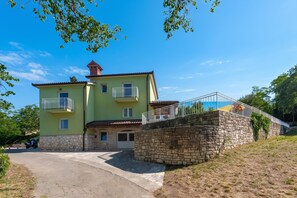 A two-story house with a stone wall entrance, a balcony, and a clear blue sky. - Villa Ester - Private Pool Escape for 8 (Krsan)