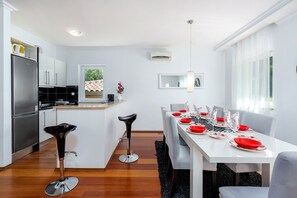 A modern kitchen with a dining area, white cabinetry, and a central island. - Villa Ester - Private Pool Escape for 8 (Krsan)
