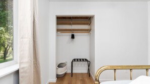 A bedroom with a bed, a window, a wooden floor, a closet with shelves, and a hanging rack. - Cozy Cabin! BBQ • Spa • Fire Pit • Kids Play Zone (Mariposa)