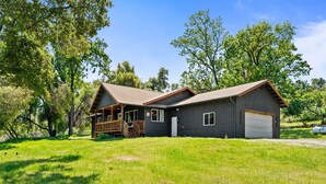 A two-story house with a wooden deck and a garage. - Cozy Cabin! BBQ • Spa • Fire Pit • Kids Play Zone (Mariposa)