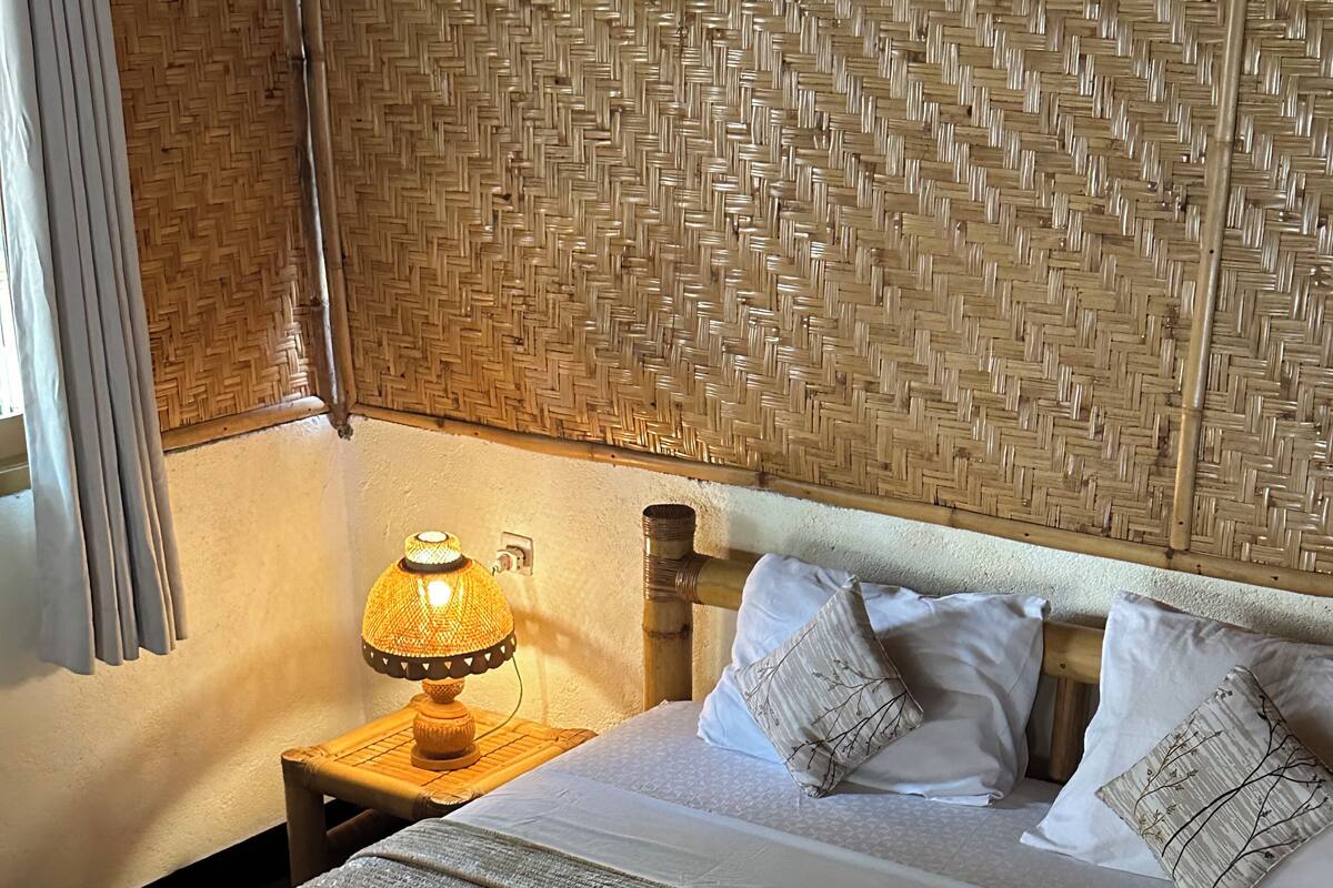 Una cama bien hecha con sábanas blancas, cabecera de madera y un diseño trenzado en la pared.