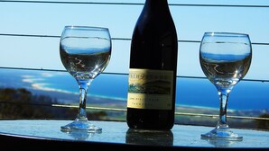 En flaska Pinot Noir-vin från Tasmanien, årgång 2006, och två vinglas står på ett bord med utsikt över ett vackert landskap.