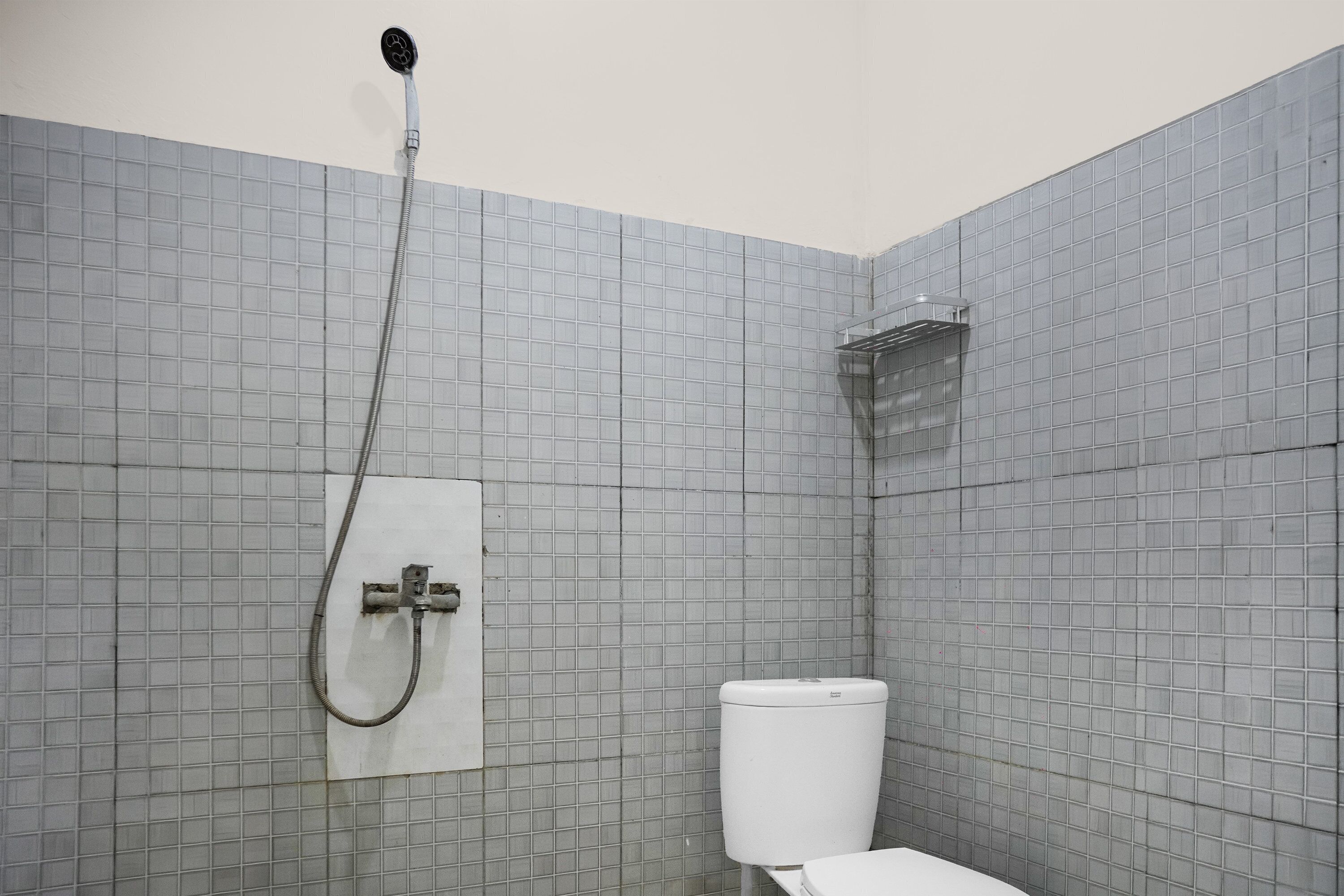 Un baño pequeño con azulejos, ducha, inodoro y toallero.