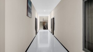Um corredor com piso lustroso, uma escada e uma porta à direita.