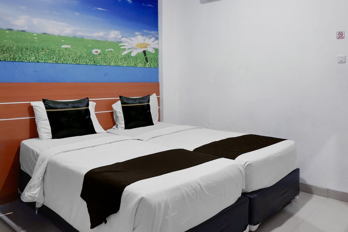 Un lit double avec une literie blanche et noire, une tête de lit fixée au mur et une grande fresque florale au-dessus du lit.