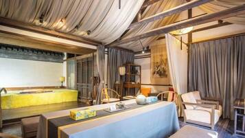 A room with a long table, chairs, a sofa, and a traditional Asian-style screen.
