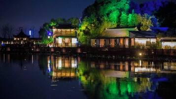 A traditional building with a reflection in the water, surrounded by trees and other structures.