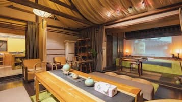 A traditional Japanese-style room with tatami flooring, a low table with tea set, and a projection screen displaying a traditional scene.