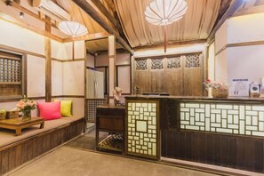 L’intérieur d’une auberge japonaise traditionnelle, avec un sol recouvert de tatamis, un comptoir d’accueil et une porte coulissante.