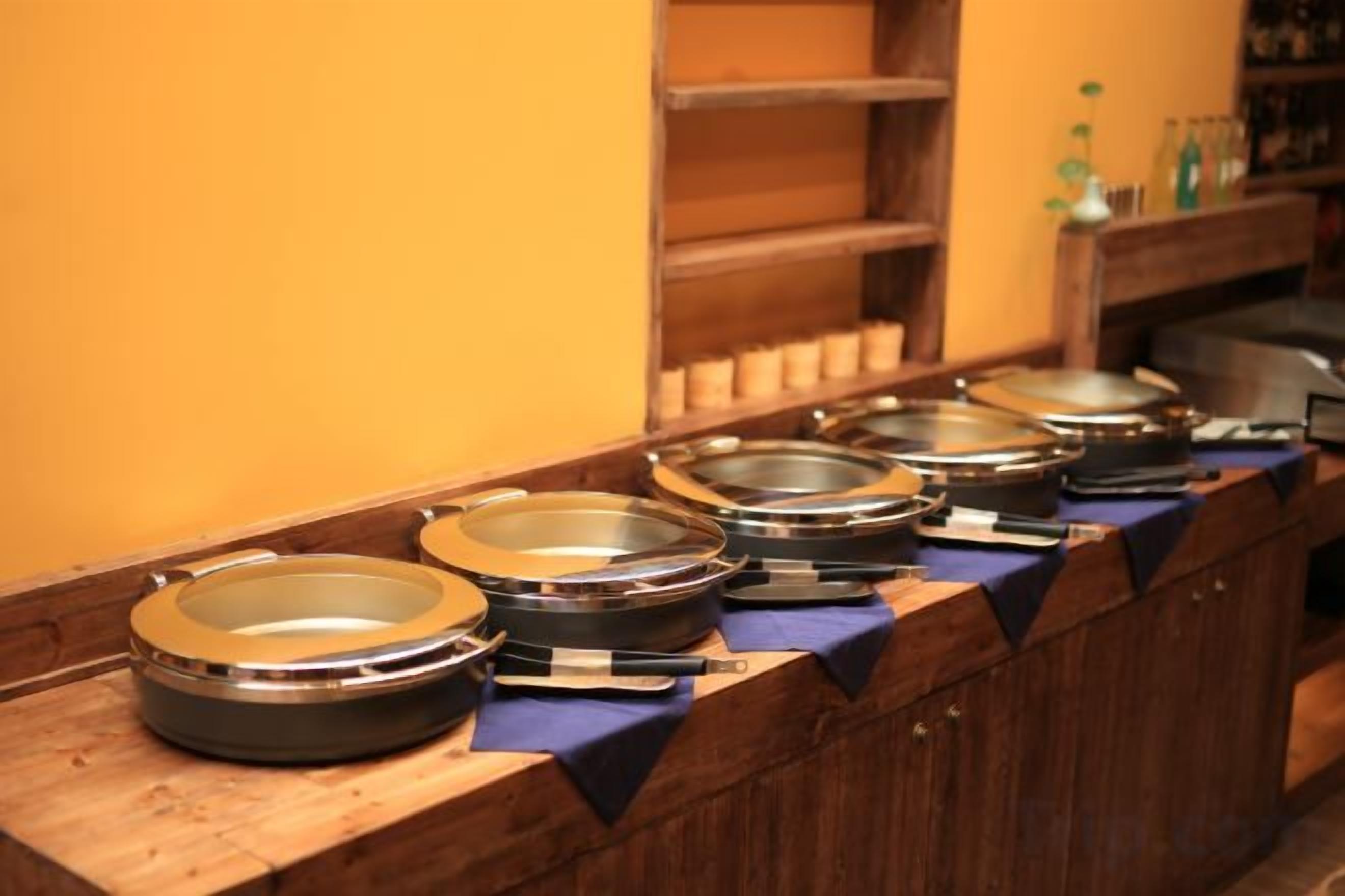 A buffet line with multiple food containers on a wooden counter.