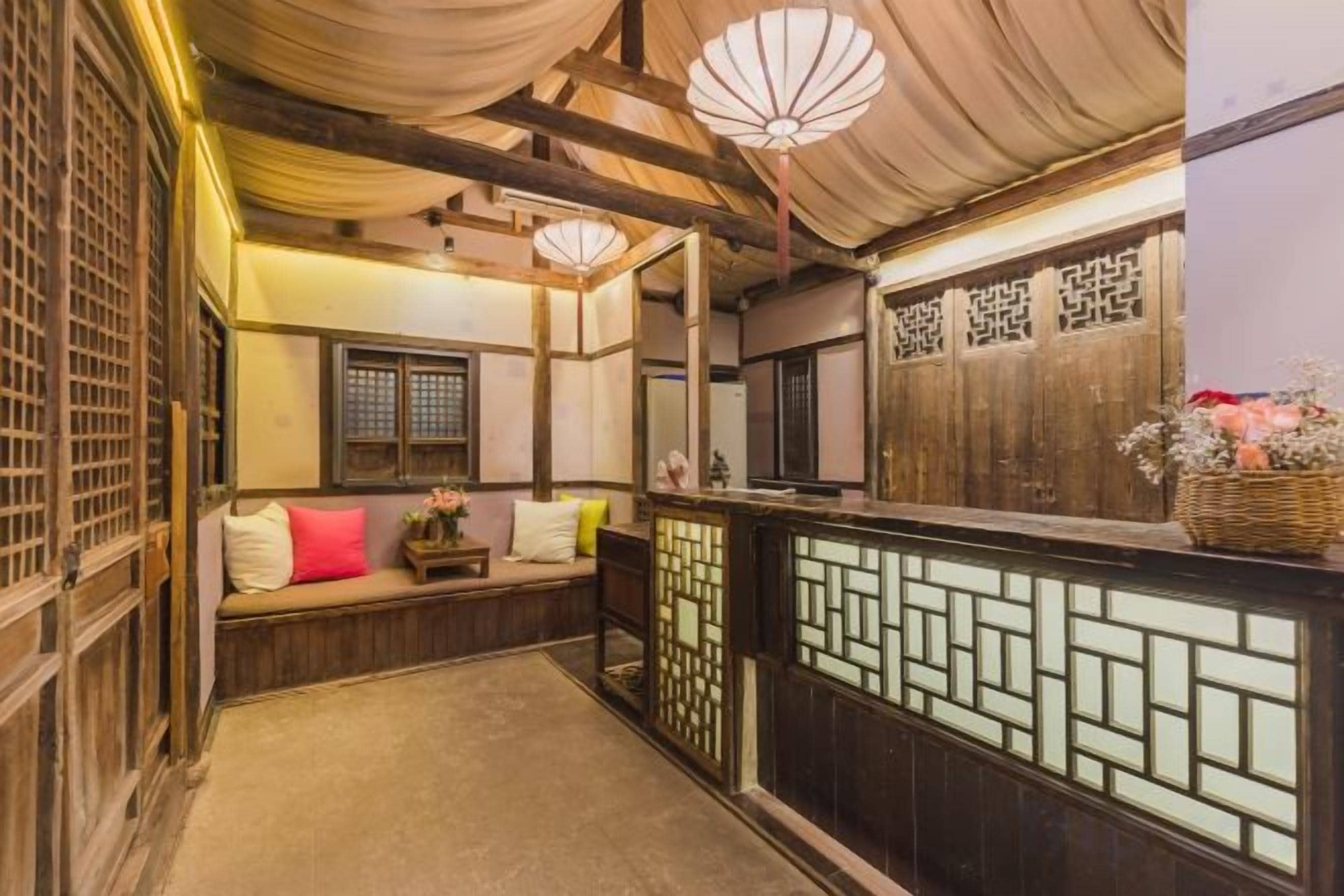 A traditional Japanese-style room with tatami flooring, a low wooden bench with cushions, and a sliding door with a geometric pattern.