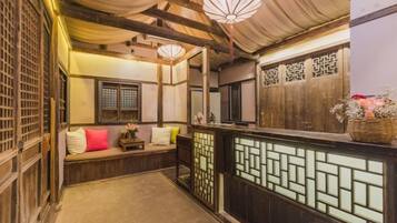 A traditional Japanese-style room with tatami flooring, a low wooden bench with cushions, and a sliding door with a geometric pattern.