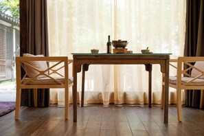 A wooden table with chairs, a window with sheer curtains, and a view of greenery outside. - Yueshang Zen Space Homestay (Zhouzhuang Ancient Town Branch) (Kunshan)