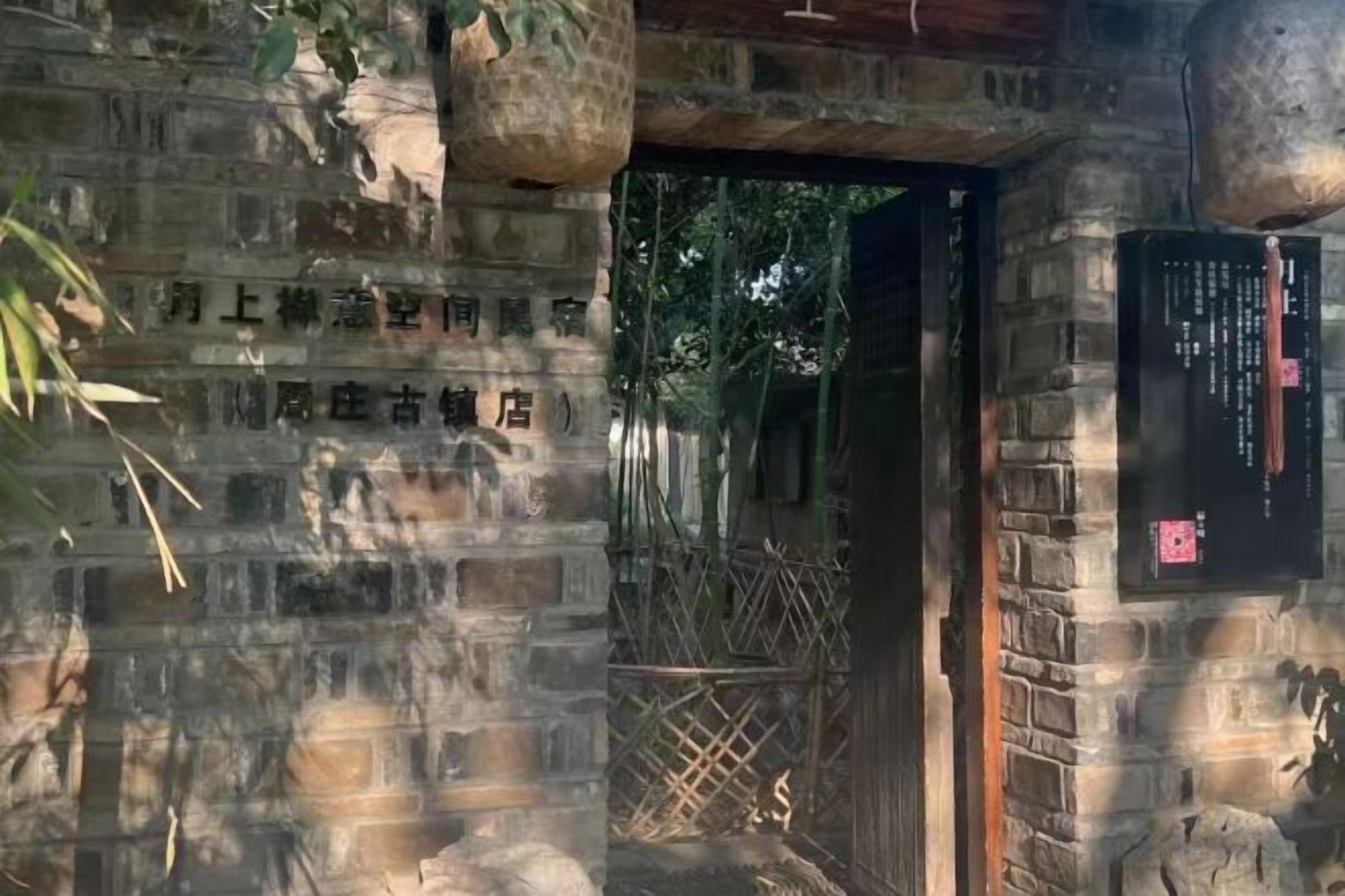 Une entrée en pierre, avec un portail traditionnel et une enseigne.
