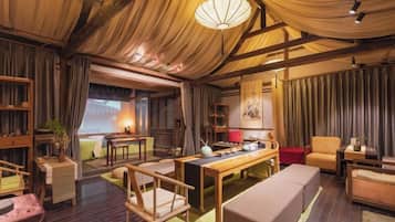 A traditional room with a wooden ceiling, a sofa, a table, and a bookshelf.