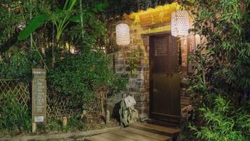 A stone entrance with a wooden staircase leading up, surrounded by dense foliage.