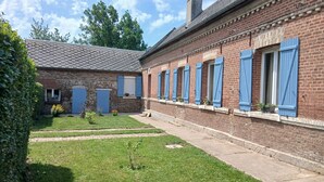 A brick building with blue shutters, a small garden, and a clear sky. - "Chez Christine," a Picardy Farmhouse, Fully Equipped for a Family Vacation. (Le Meillard)