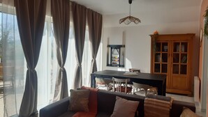 A living room with a sofa, a dining table, and a kitchen area with cabinets. - "Chez Christine," a Picardy Farmhouse, Fully Equipped for a Family Vacation. (Le Meillard)