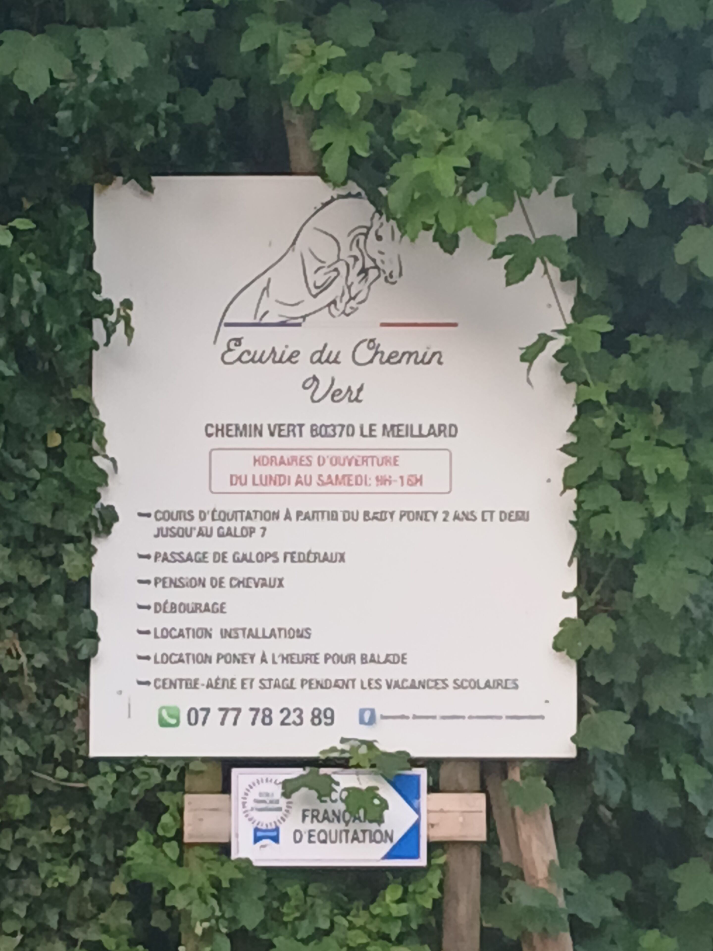 Schild für 'Ecurie du Chemin Vert' mit Annehmlichkeiten wie Reiten, Reitzentrum und einer Kontaktnummer.