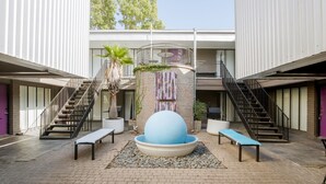 A courtyard with a central seating area, two staircases, and a building with a balcony. - 1BR W Alabama Montrose Sueño Apt 6, Med Center! (Houston)