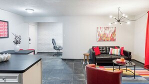 A modern living room with a sofa, coffee table, and a dining area with a counter and chairs. - 1BR W Alabama Montrose Sueño Apt 6, Med Center! (Houston)