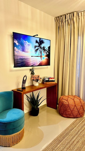 Ein Wohnzimmer mit Fernseher, einer Couch, einem Couchtisch, einer Pflanze und einem Sitzsack.