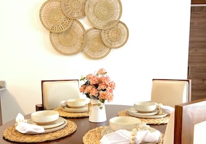 A dining table set with plates, bowls, and a vase of flowers. - Rooftop Bliss Cozy 2-bedroom condo in soothing Punta Cana with private rooftop (Punta Cana)