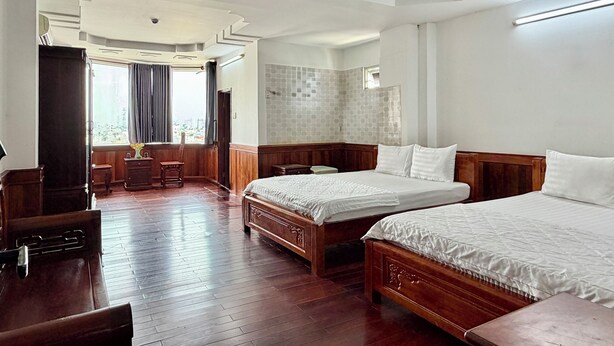 Een hotelkamer met twee bedden, een houten vloer, uitzicht op de stad en een badkamer met betegelde wanden.