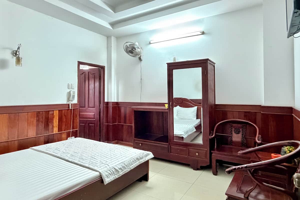 Una stanza con un letto, un armadio in legno, una sedia e una scrivania.