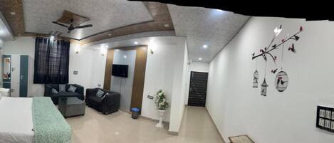 A hotel room with a bed, a sofa, a TV, and a ceiling fan.