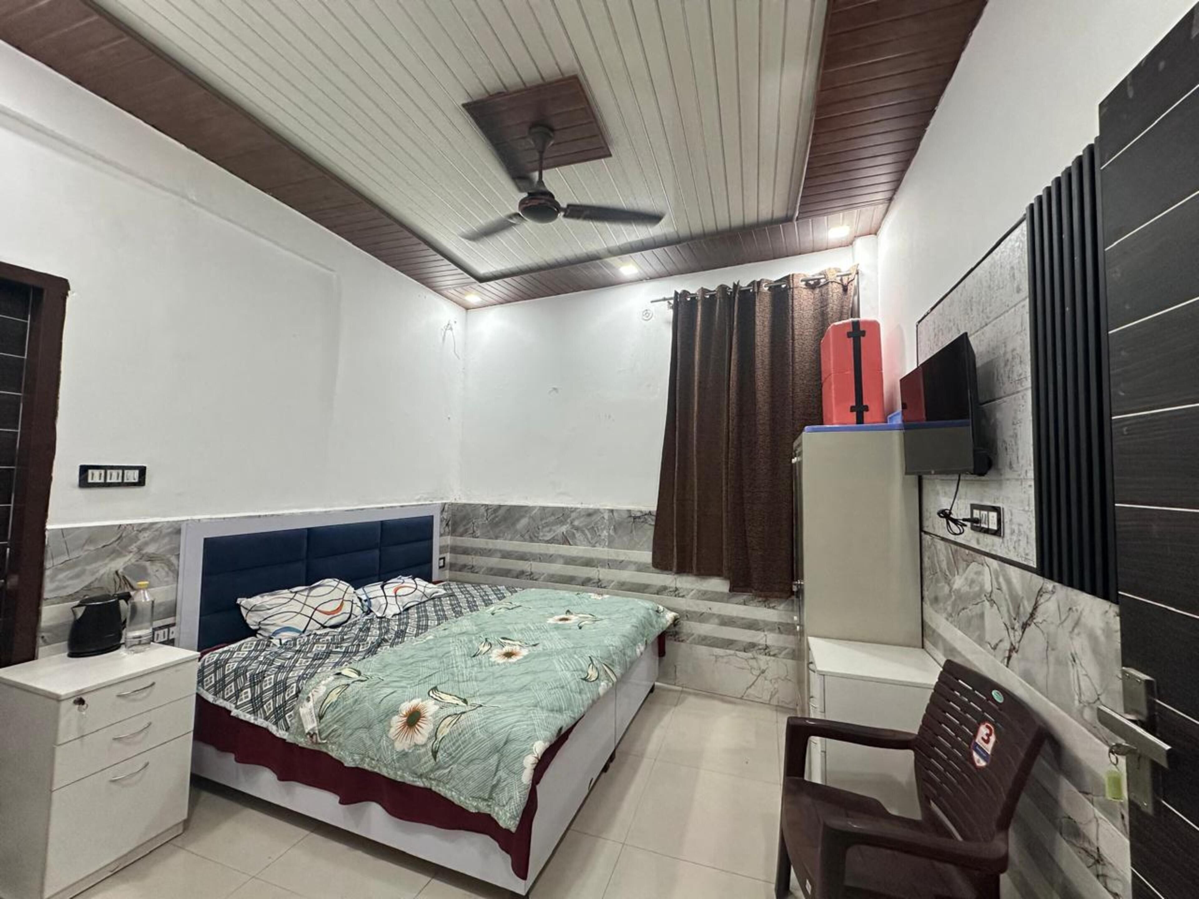 Un dormitorio con cama, escritorio, silla, televisor y ventilador de techo.
