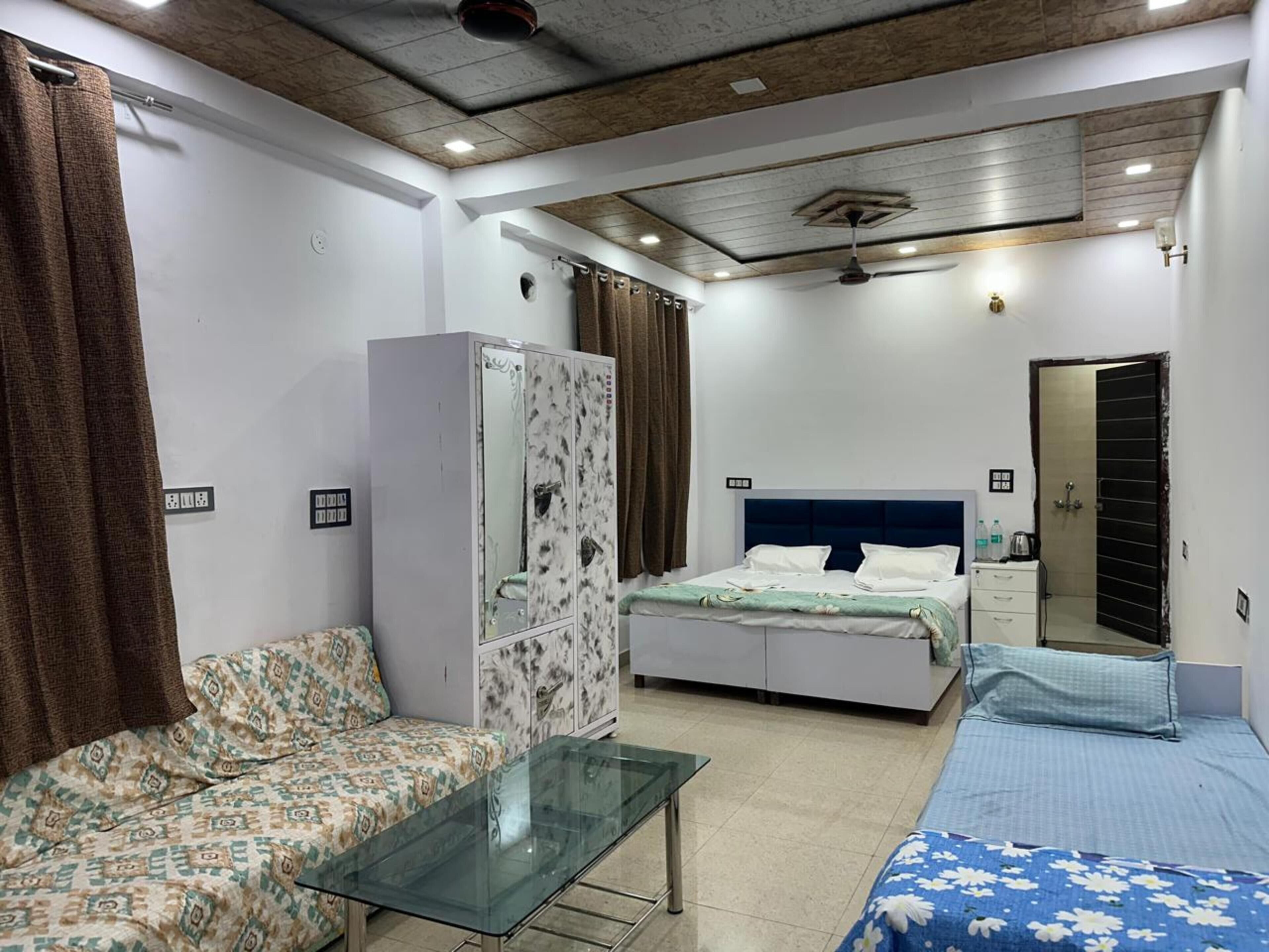 A bedroom with a bed, a sofa, a glass table, a wardrobe, and a mirror.