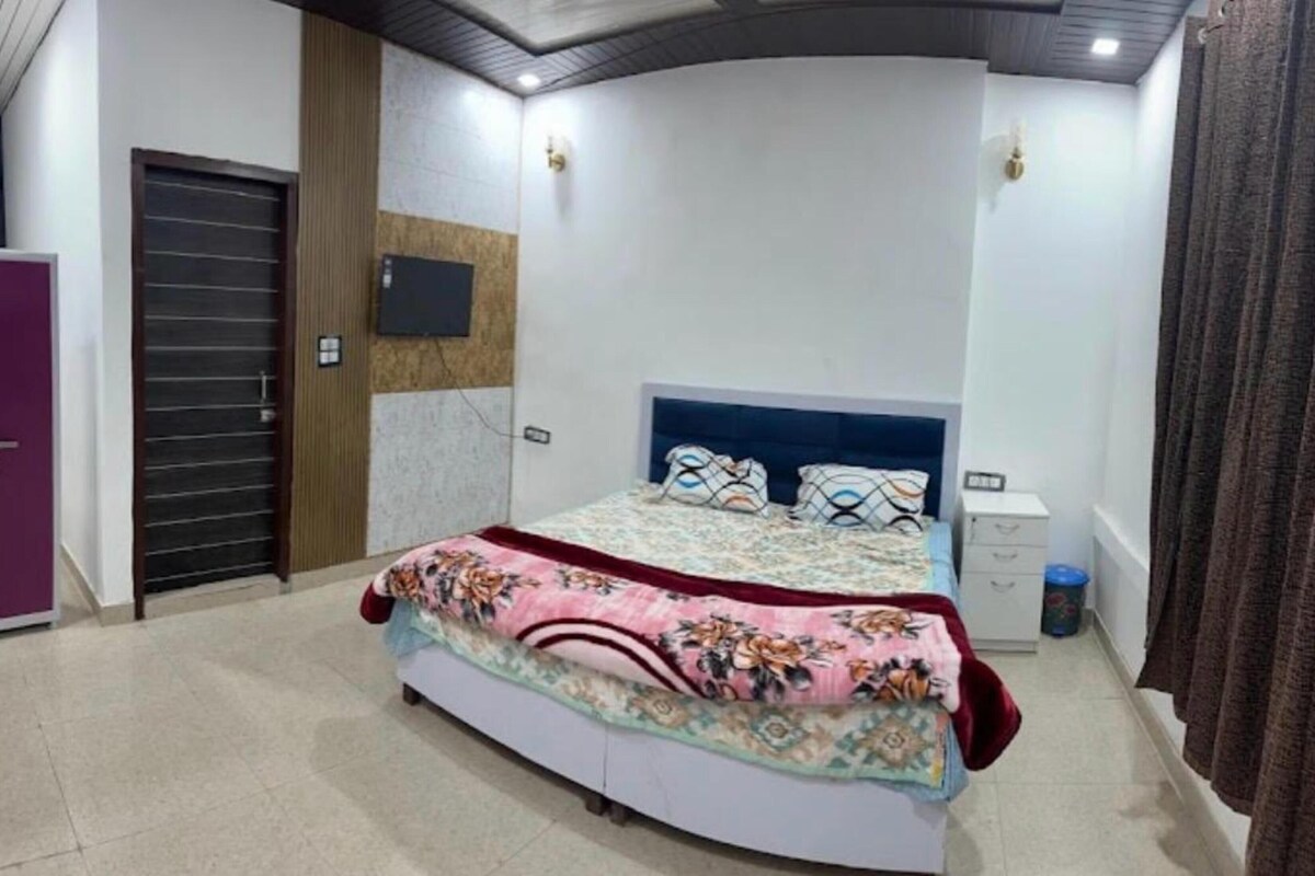 A bedroom with a bed, a wardrobe, a door, and a wall-mounted light fixture.