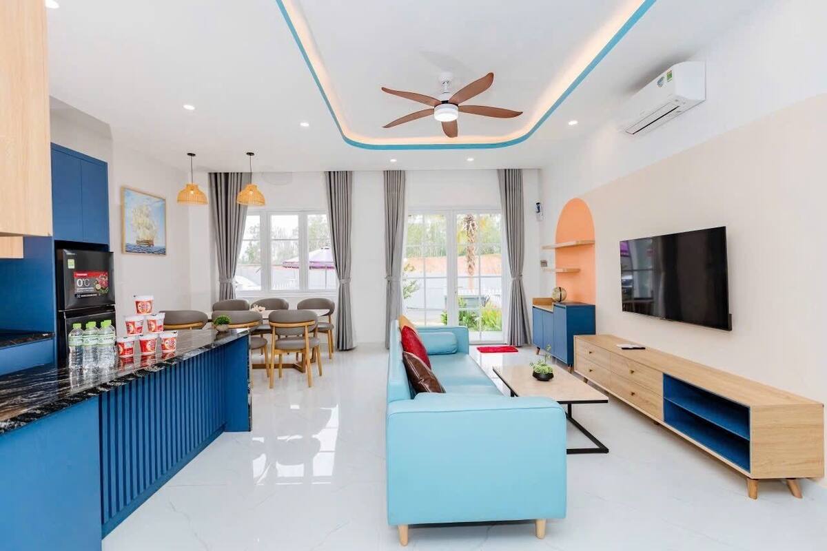A modern living room with a sofa, TV, and a dining area with chairs and a table.