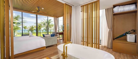 Una habitación de hotel moderna con una cama grande, una bañera, un sofá y vistas a palmeras.
