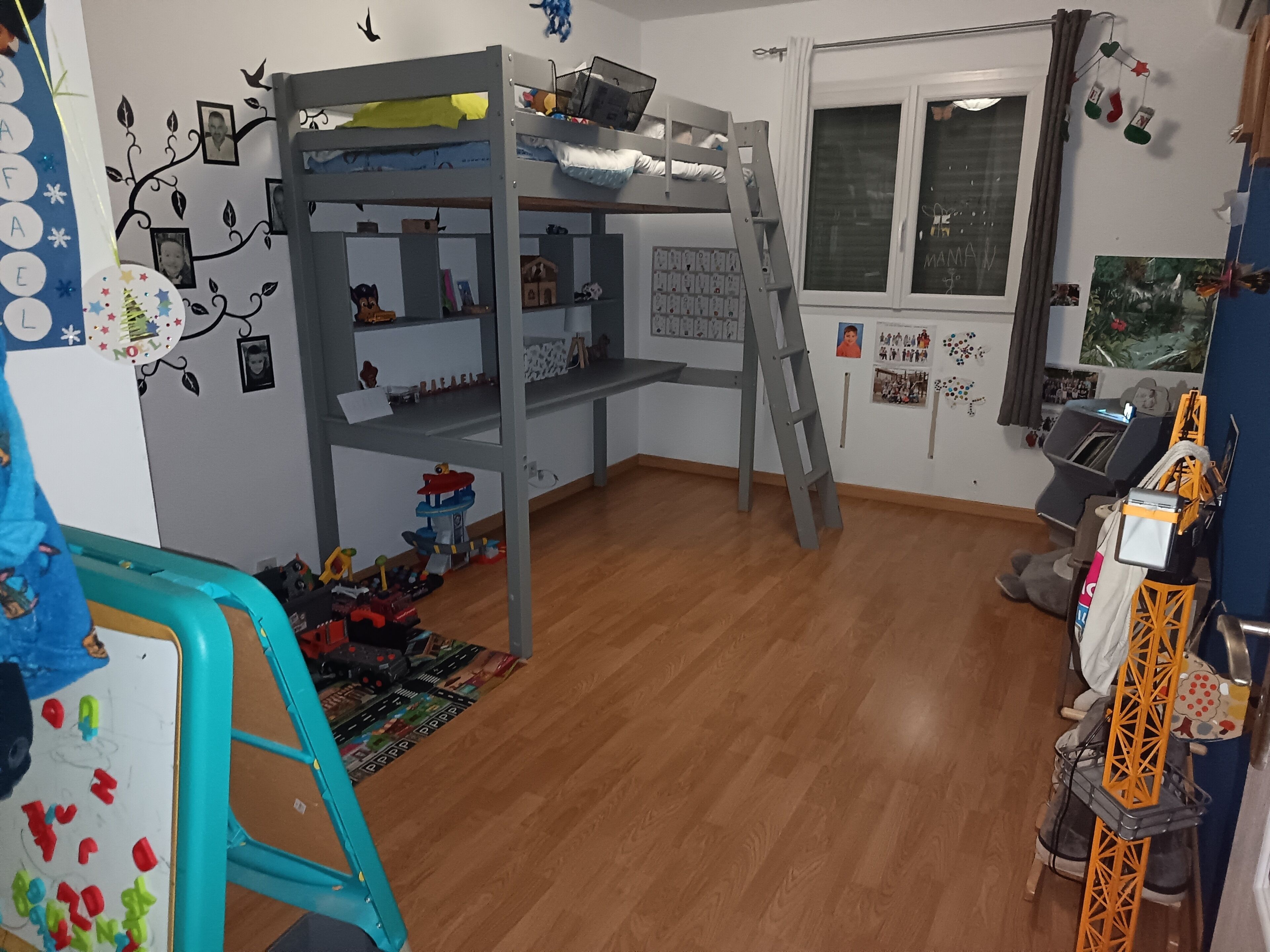 Habitación infantil con literas, juguetes, un escritorio y una ventana.