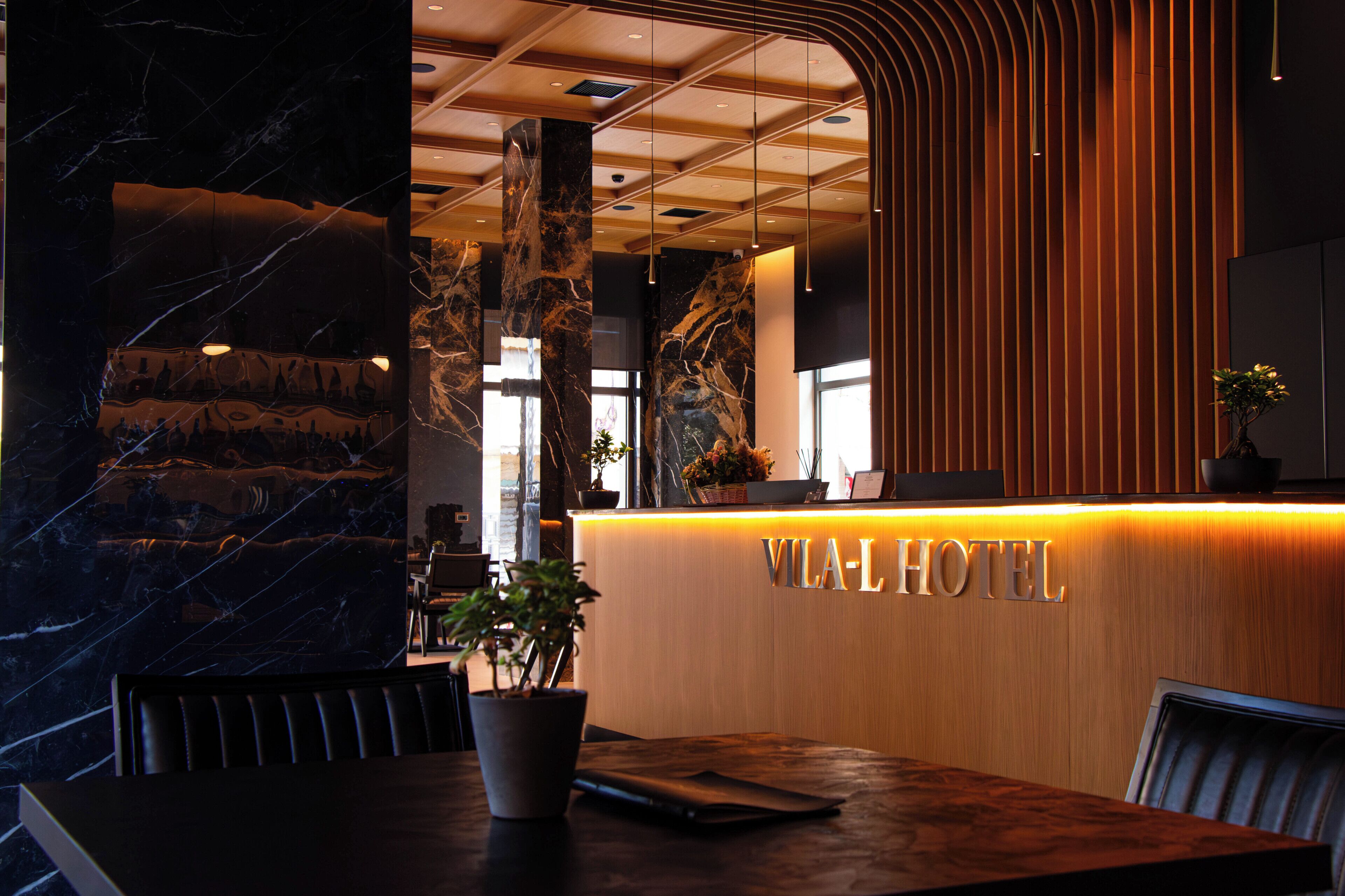 Un mostrador de recepción con un letrero 'VILA-L', columnas de mármol y una decoración interior moderna.