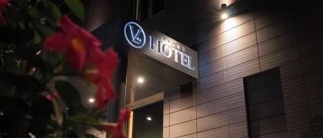 A hotel sign with a logo and the word 'HOTEL' illuminated.