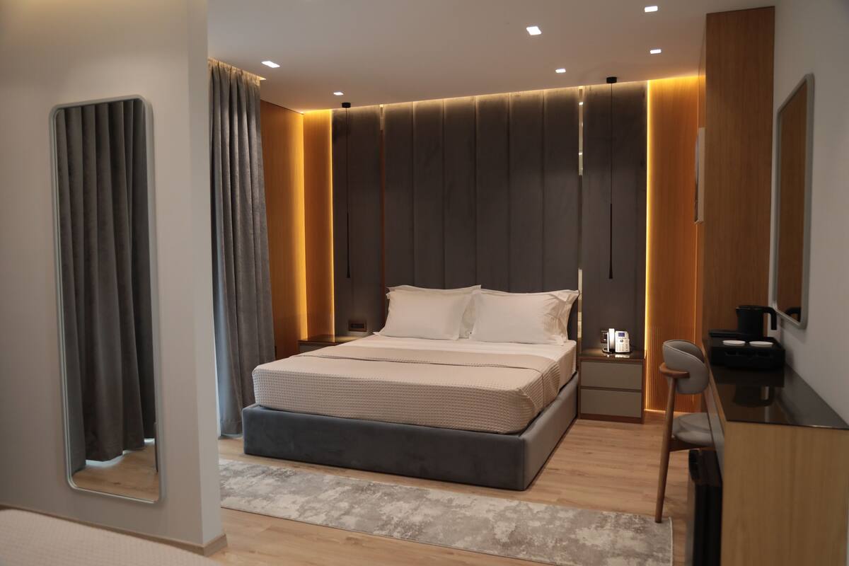 A modern bedroom with a large bed, bedside tables, a desk, and a chair.
