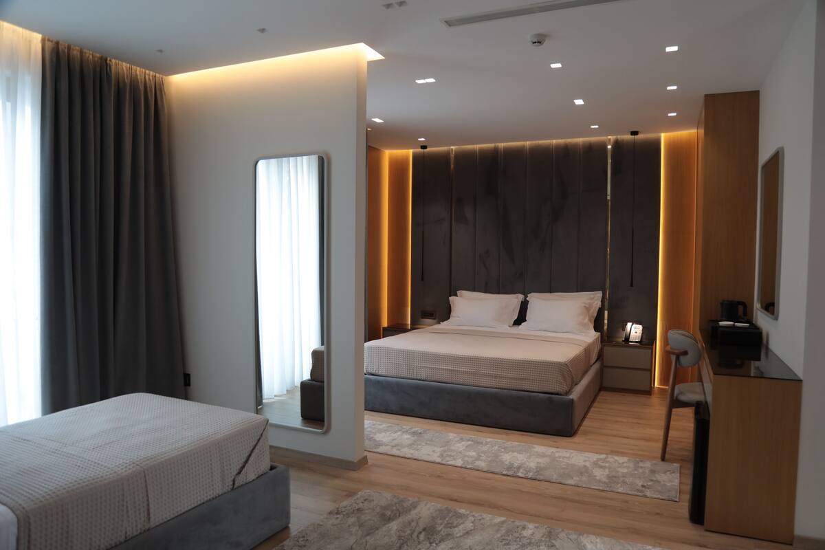 A modern bedroom with a bed, bedside table, and a desk with a chair.