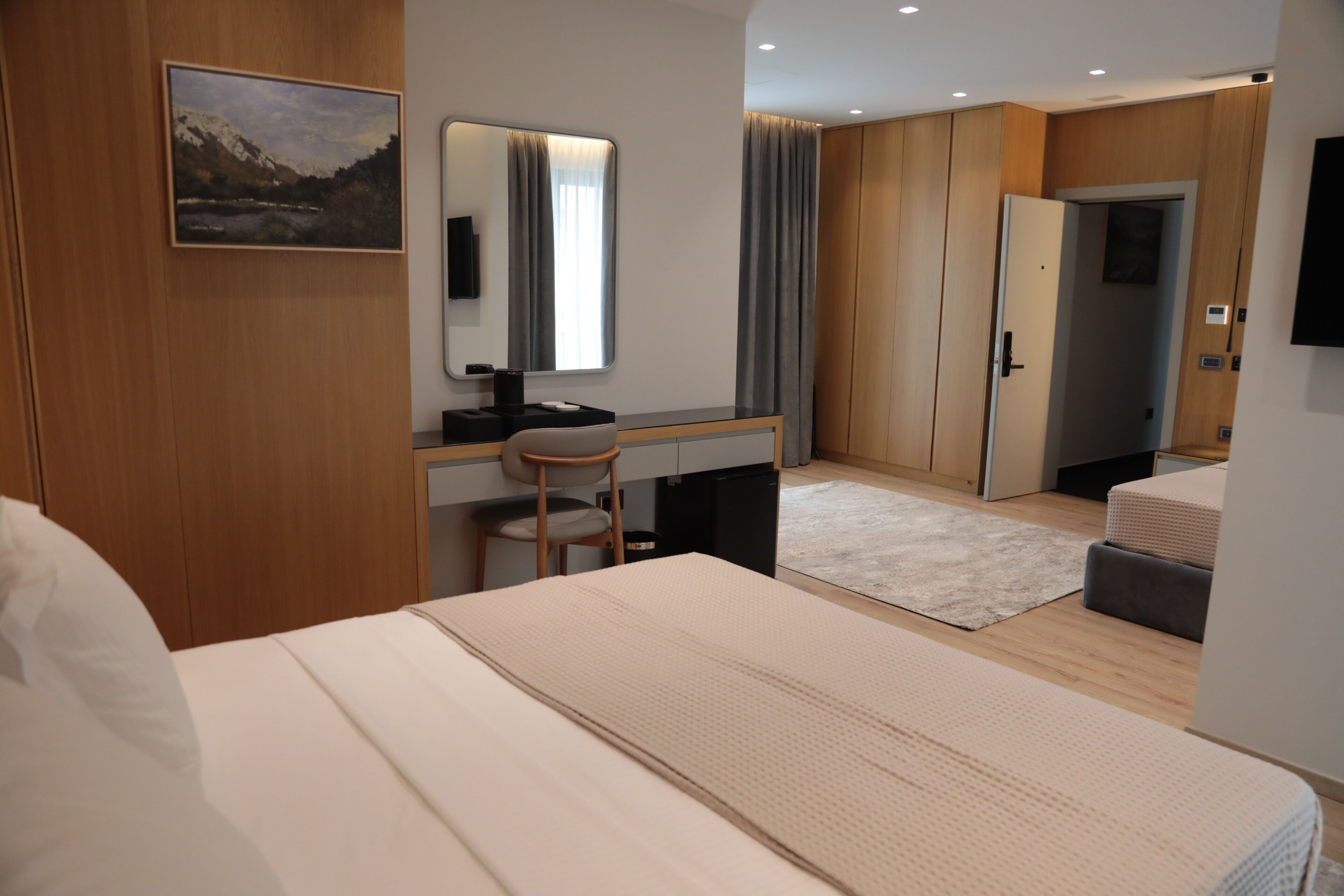 Una habitación de hotel moderna con cama, escritorio, silla y un espejo grande.