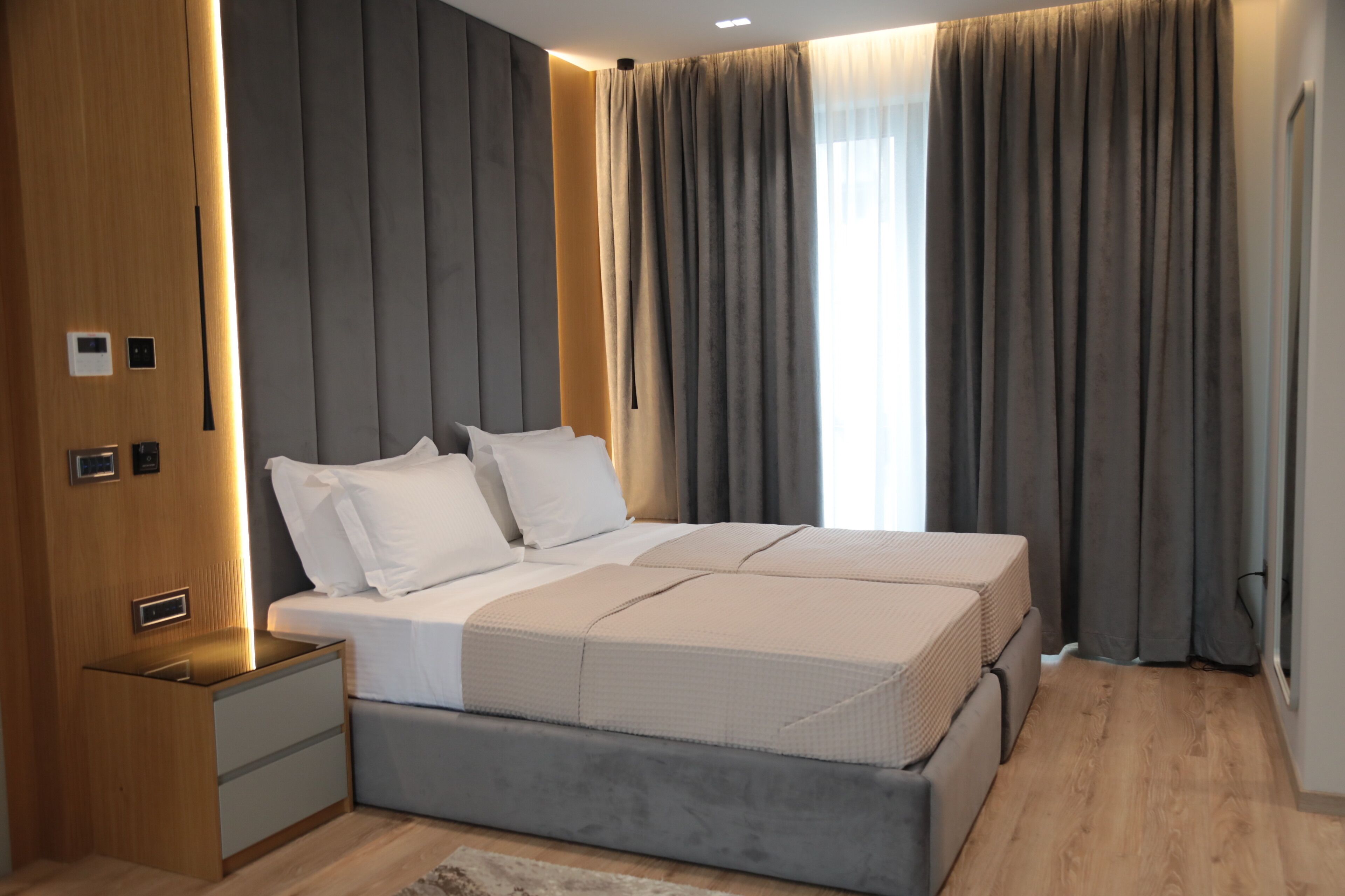 A modern bedroom with a large bed, built-in nightstands, and a wooden wardrobe.