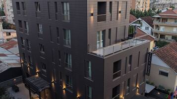Un hôtel à plusieurs étages, doté d’un design moderne, comprenant des balcons, un espace extérieur couvert avec des sièges et une enseigne indiquant le nom « Yilal Hotel ».