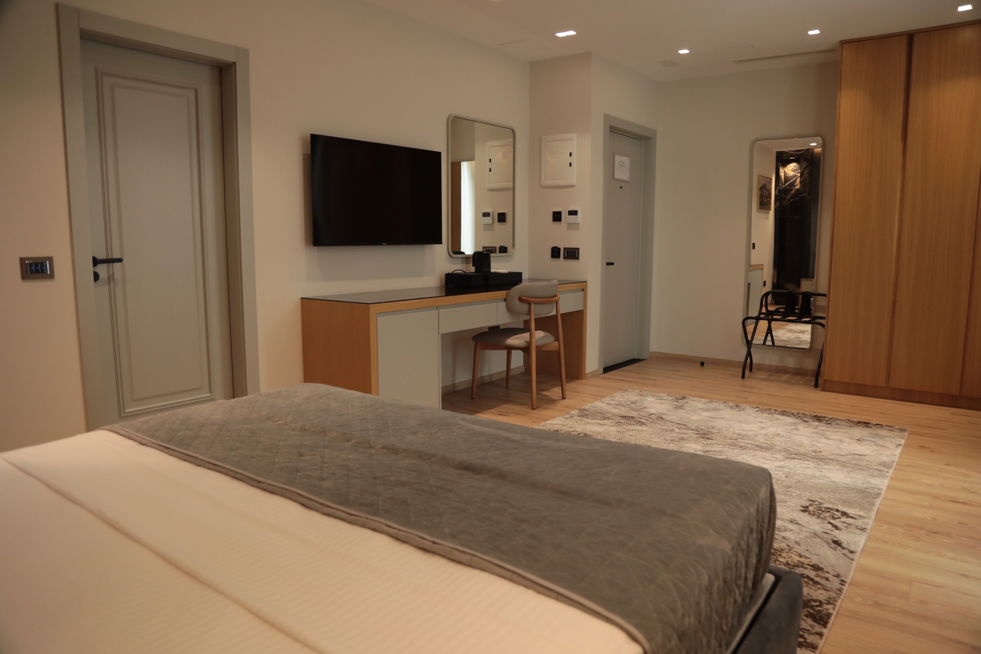Un dormitorio con cama, escritorio, silla, televisor y armario.