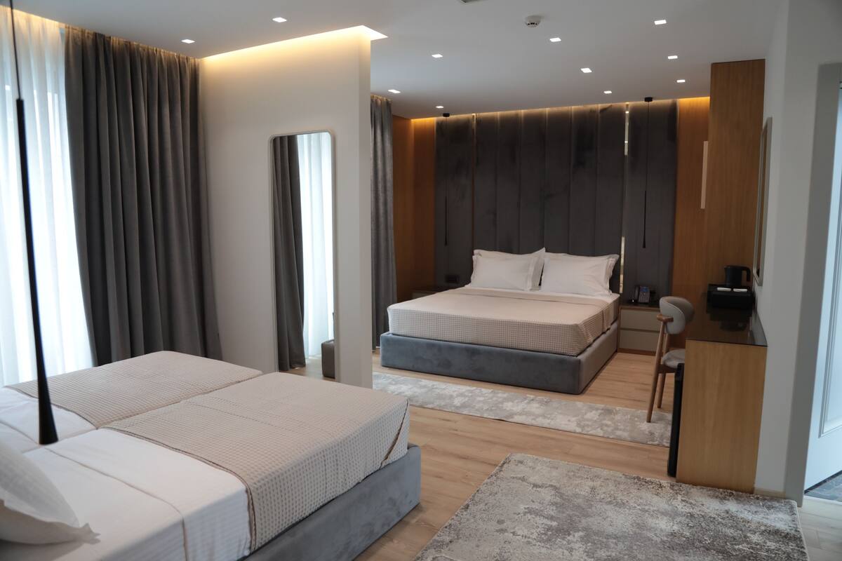 A modern bedroom with a large bed, bedside tables, a desk, and a wardrobe.