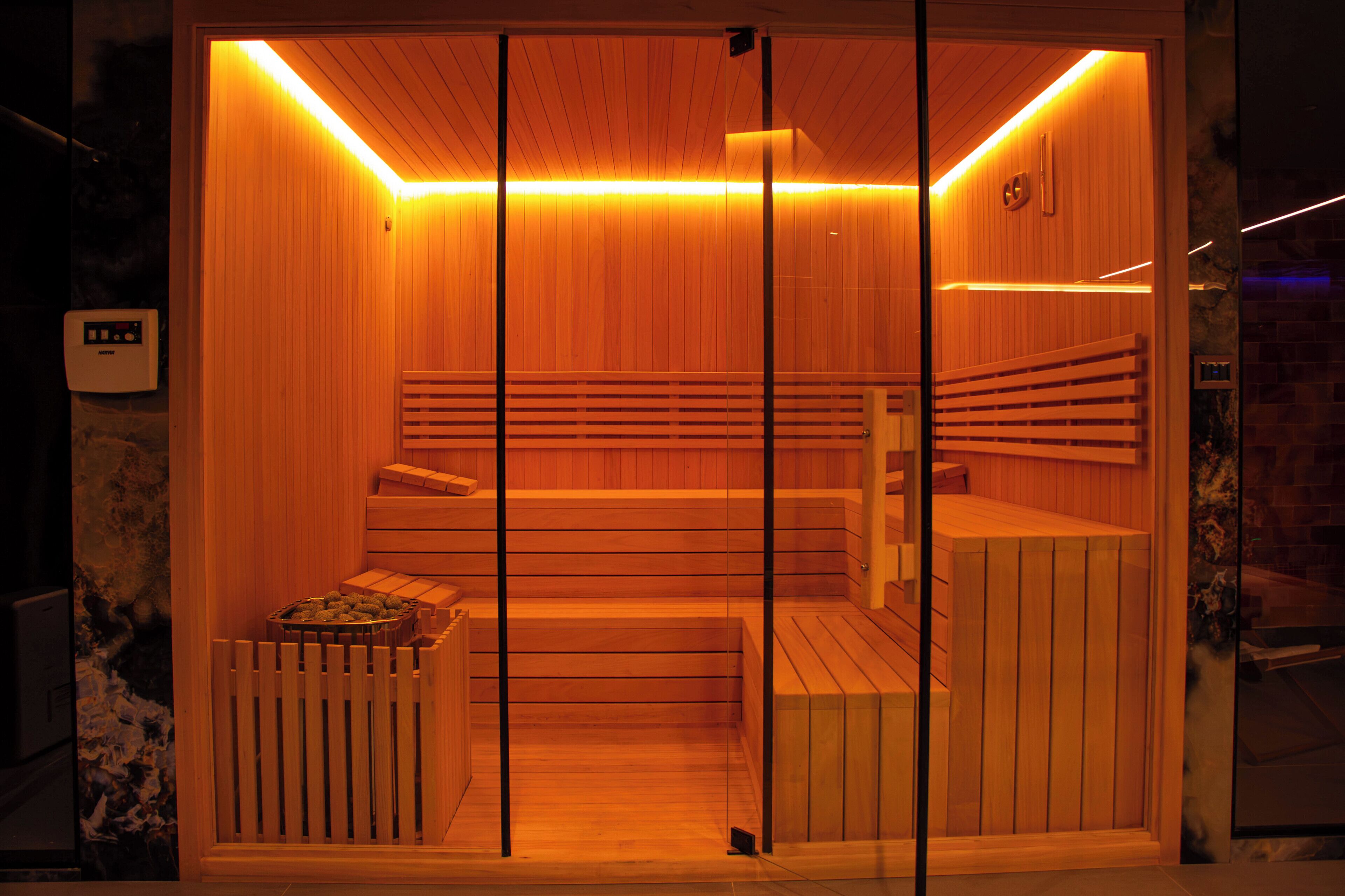 Una sauna con pareti in legno, una panca e un pannello di controllo.