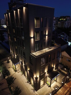 A multi-story hotel with a modern design, featuring balconies and a well-lit entrance. - Vila-L Hotel (Tirana)